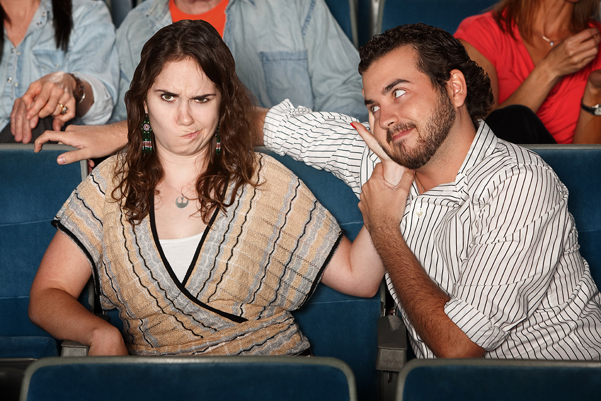 woman pushing away flirty man on a cinema date