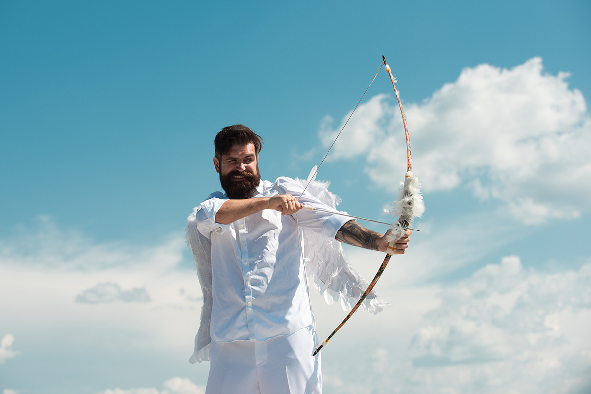 Man dressed as cupid aiming bow