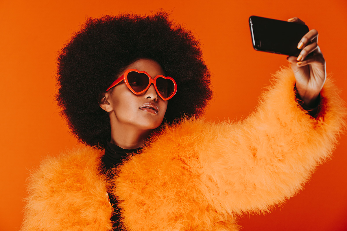 woman dressed in orange taking a selfie on smartphone