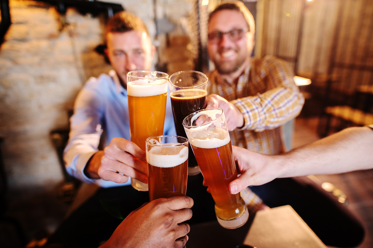 men cheering with schooners of beer