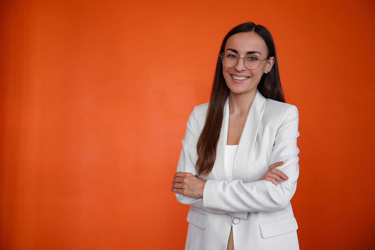 business woman in white suit smiling and posing with crossed arms