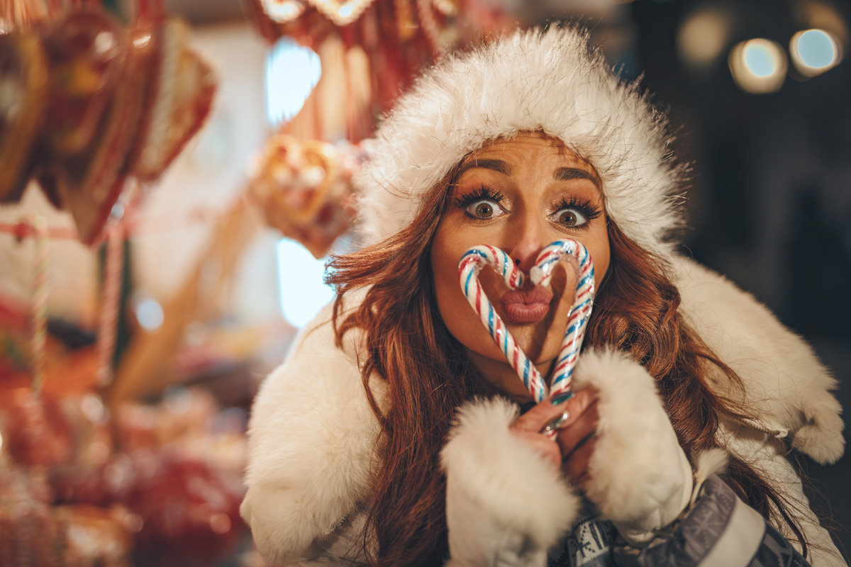lady wearing winter clothes blowing a kiss through heart made from candycanes
