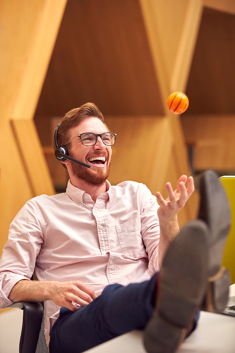 office worker on a headset call juggling a small basketball