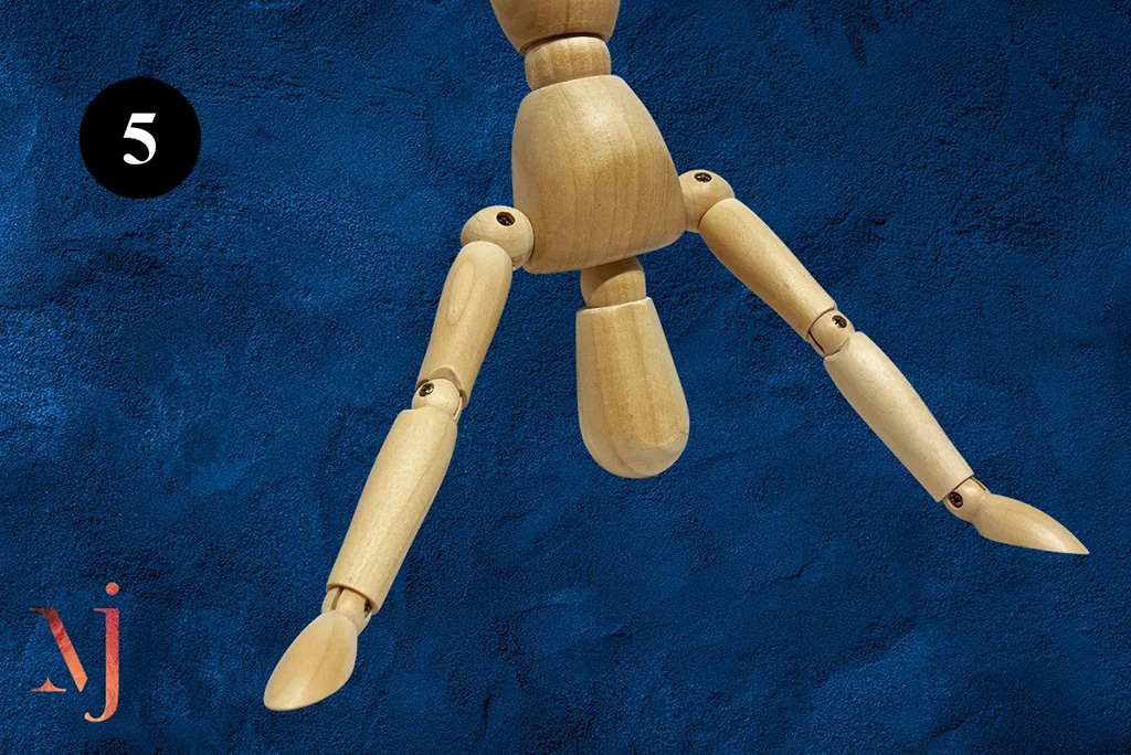 wooden mannequin hanging upside down with arms splayed