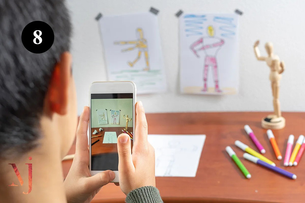 man taking photo of desk covered in drawings and wooden mannequin