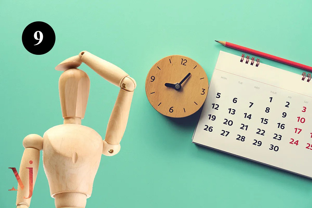 wooden mannequin rubbing head next to clock and calendar