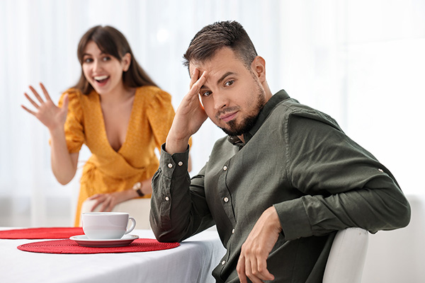 man turning away from a woman enthusiastically greeting him