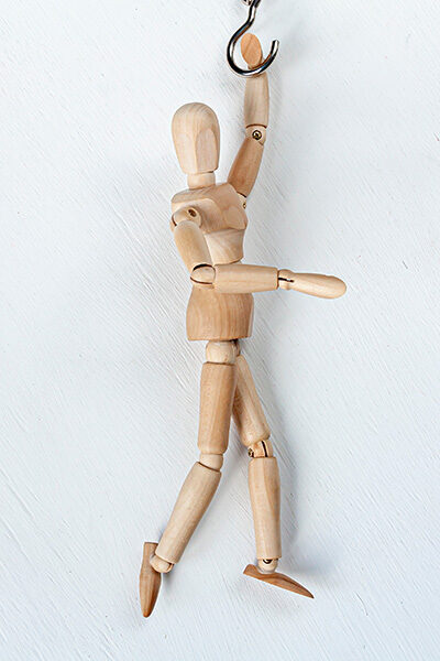 wooden mannequin hanging from metal hook