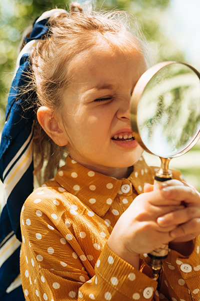 little girl looking through a magnifying glass