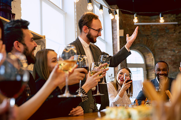 smartly dressed group of people raising a toast with wine glasses