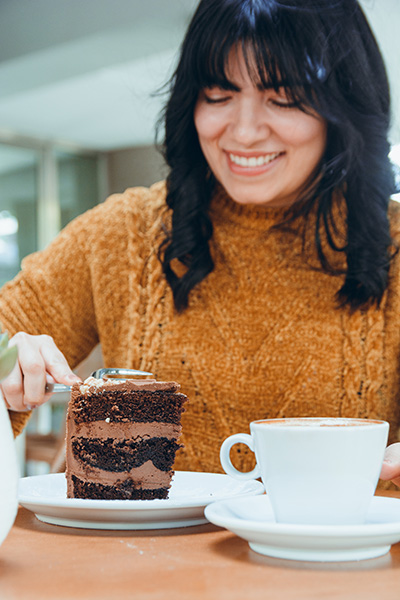 Happy woman eating a slice of chocolate cake