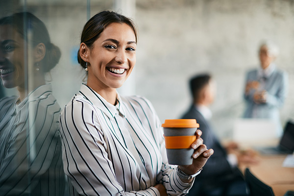 happy corporate woman holding a coffee mug in boardroom