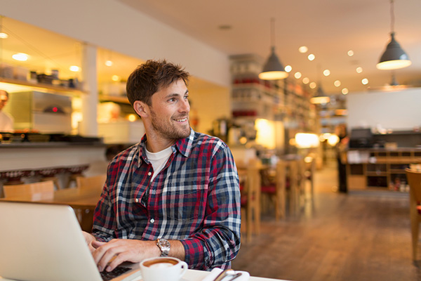 man in his thirties working on laptop in a cafe